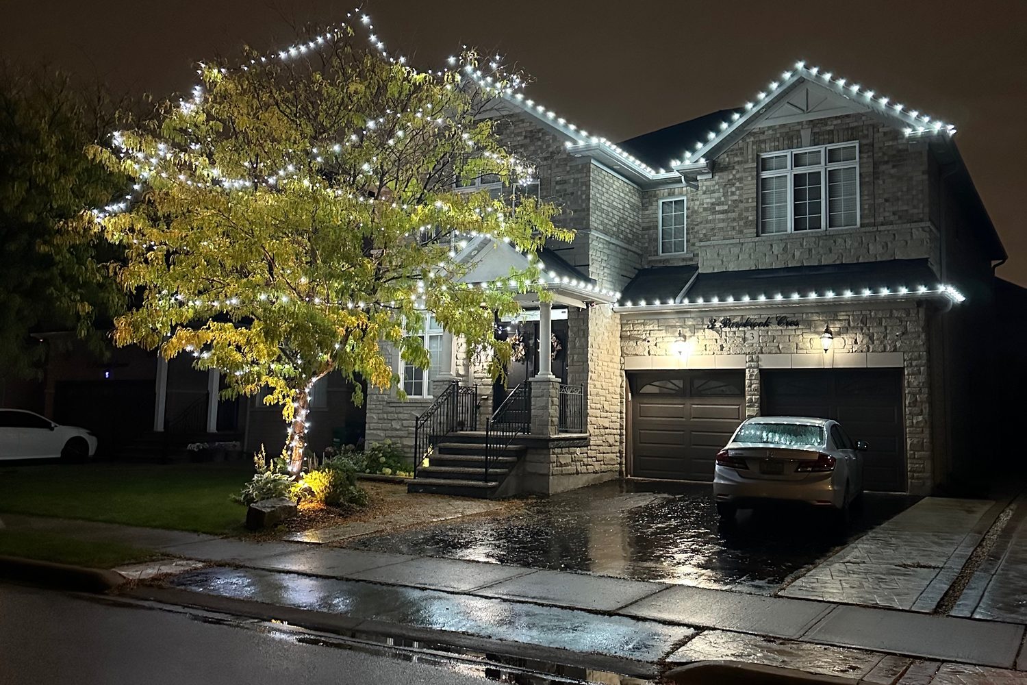 Two-storey home with white roofline lights and a light-wrapped tree