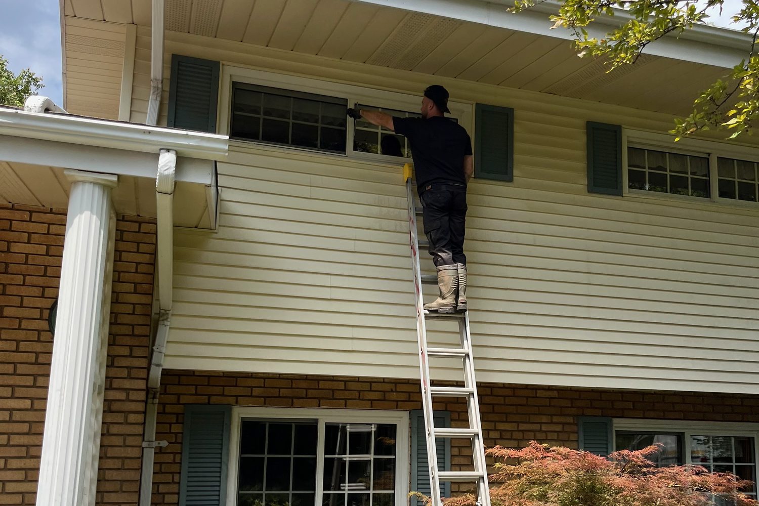 Jake on a ladder cleaning gutters and upper windows