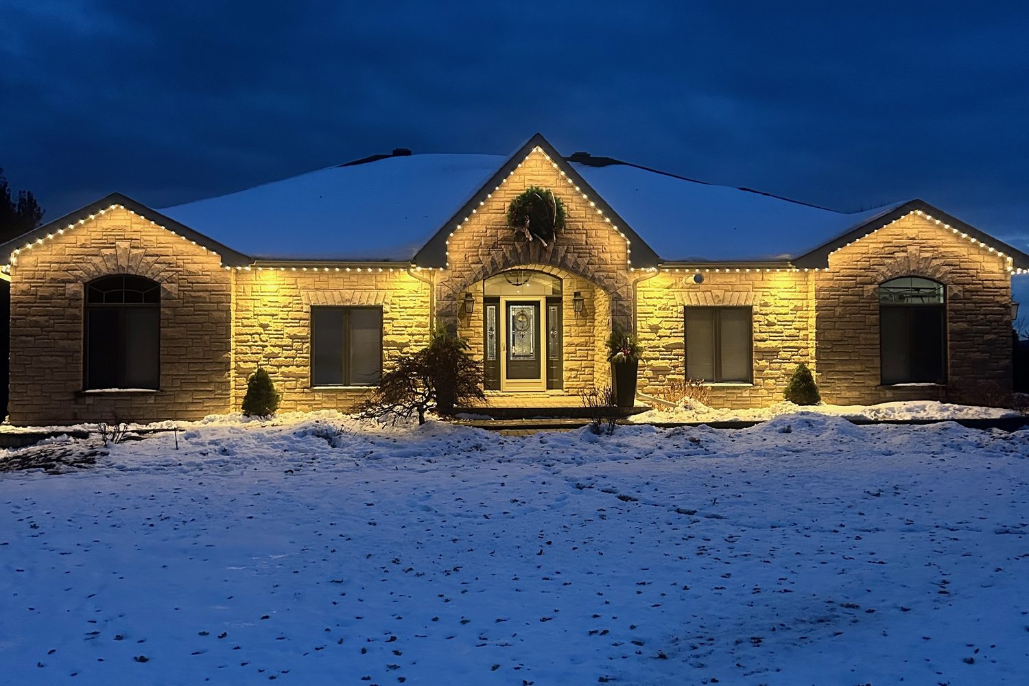 Stone home with warm-white permanent roofline lighting