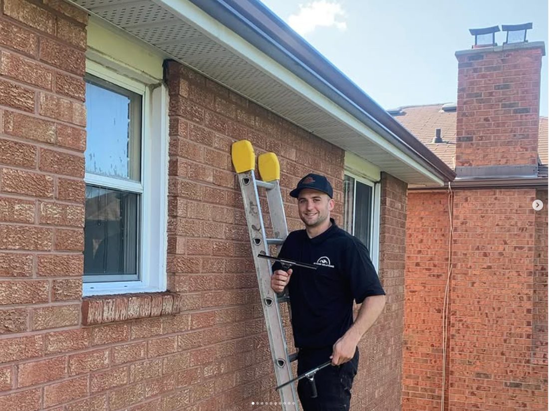 Jake cleaning windows on a brick home with a professional water-fed pole