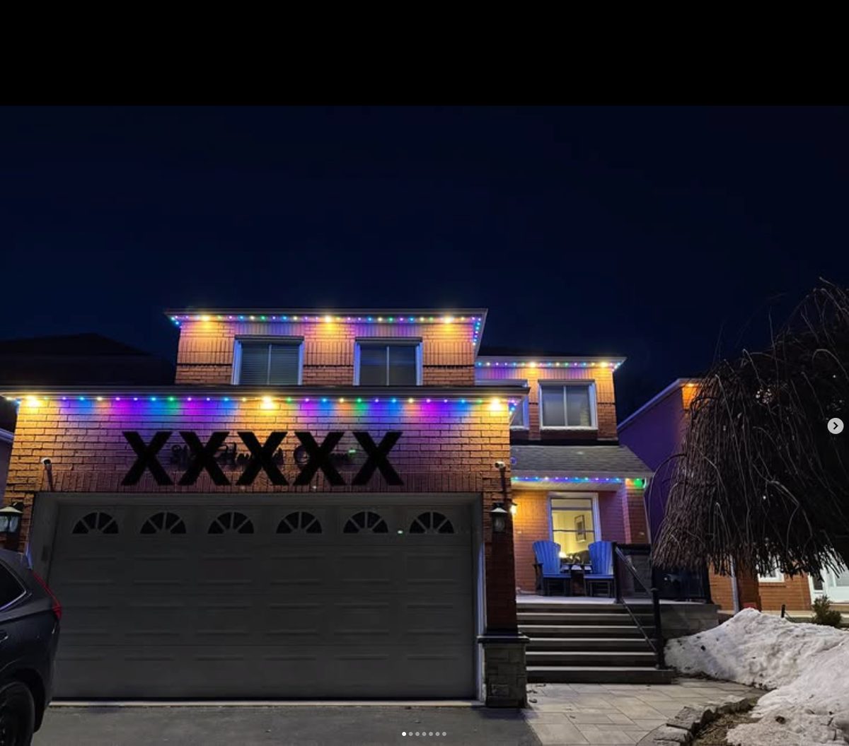 Home lit in multiple colours with permanent lighting on a snowy winter evening