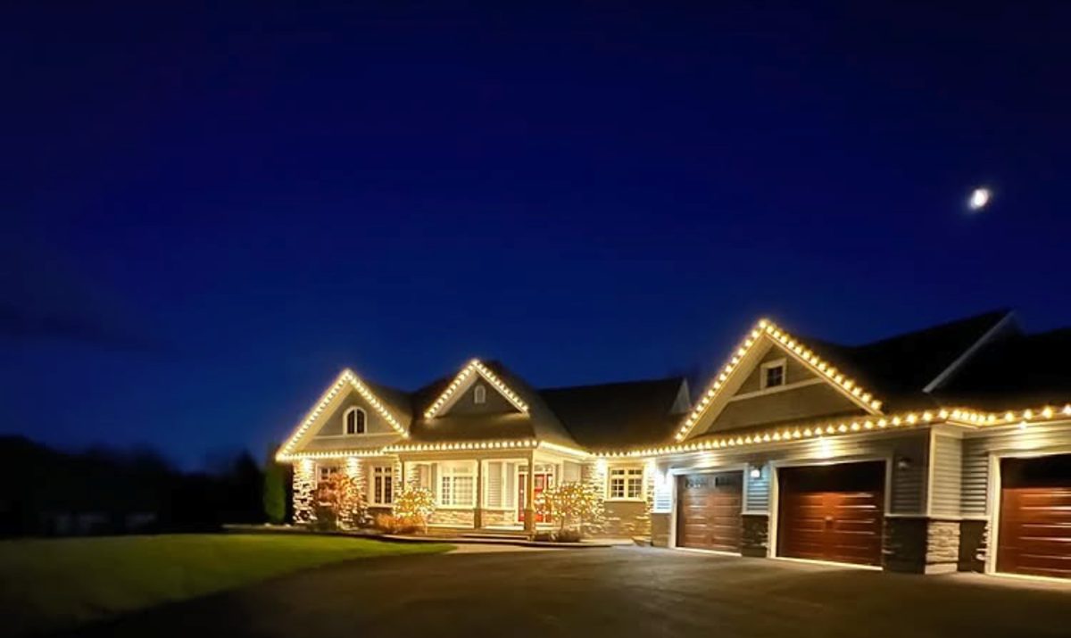 Long ranch-style home with warm permanent lighting glowing in the evening
